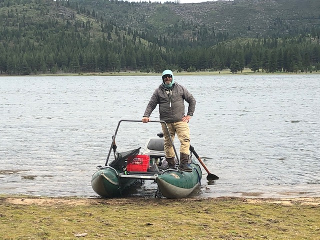 A man pushing off in a personal pontoon fishing boat at the edge of Round Valley Reservoir